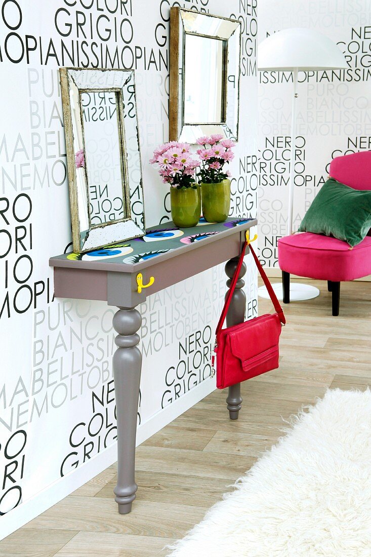DIY console table against wallpaper with pattern of lettering