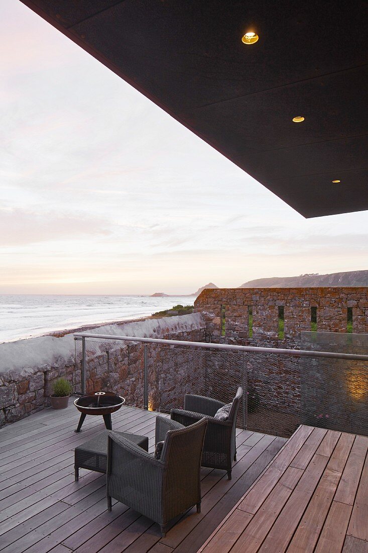 Blick von der Terrasse mit Sesseln auf Meer und Sonnenuntergang