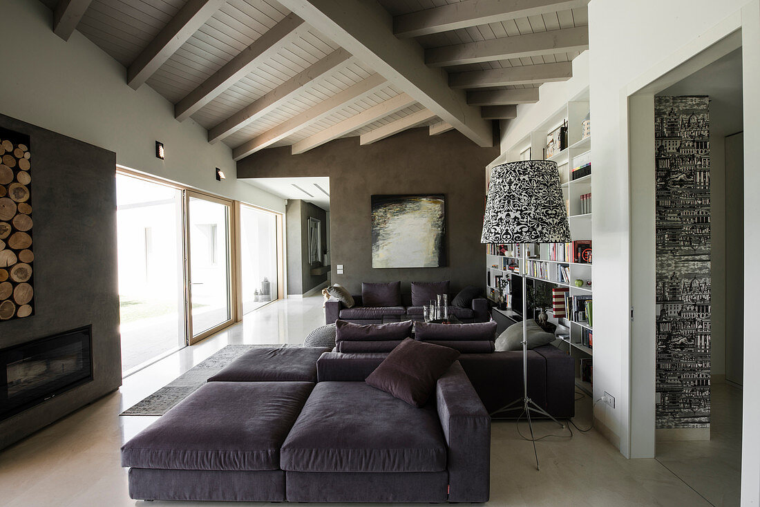 Elegante Lounge mit grauer Polstergarnitur, Kamin und Glasfront