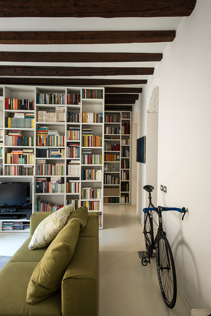Fahrrad hinter dem Sofa im Wohnzimmer mit Bücherregalen