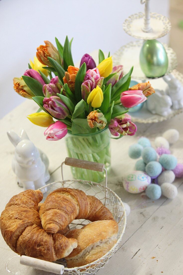 Croissants, Easter bunny and vase of tulips on wooden table