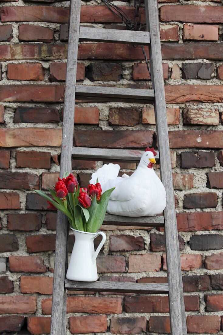 DIY-Henne aus Stoff und Tulpen in weißem Krug auf rustikaler Holzleiter