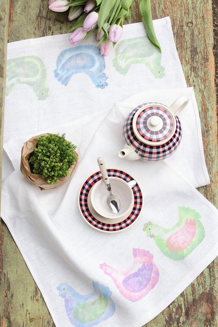 DIY-Tischläufer mit Hennenmotiv, Grünpflanze und Teegeschirr