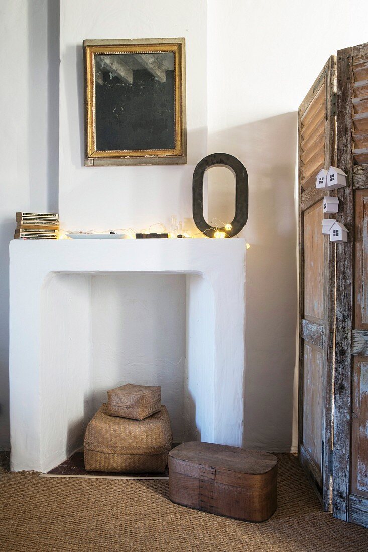 Disused white fireplace next to vintage screen in renovated country house