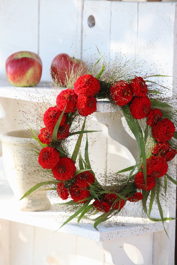 Wreath of red zinnias and switchgrass hung from shelf