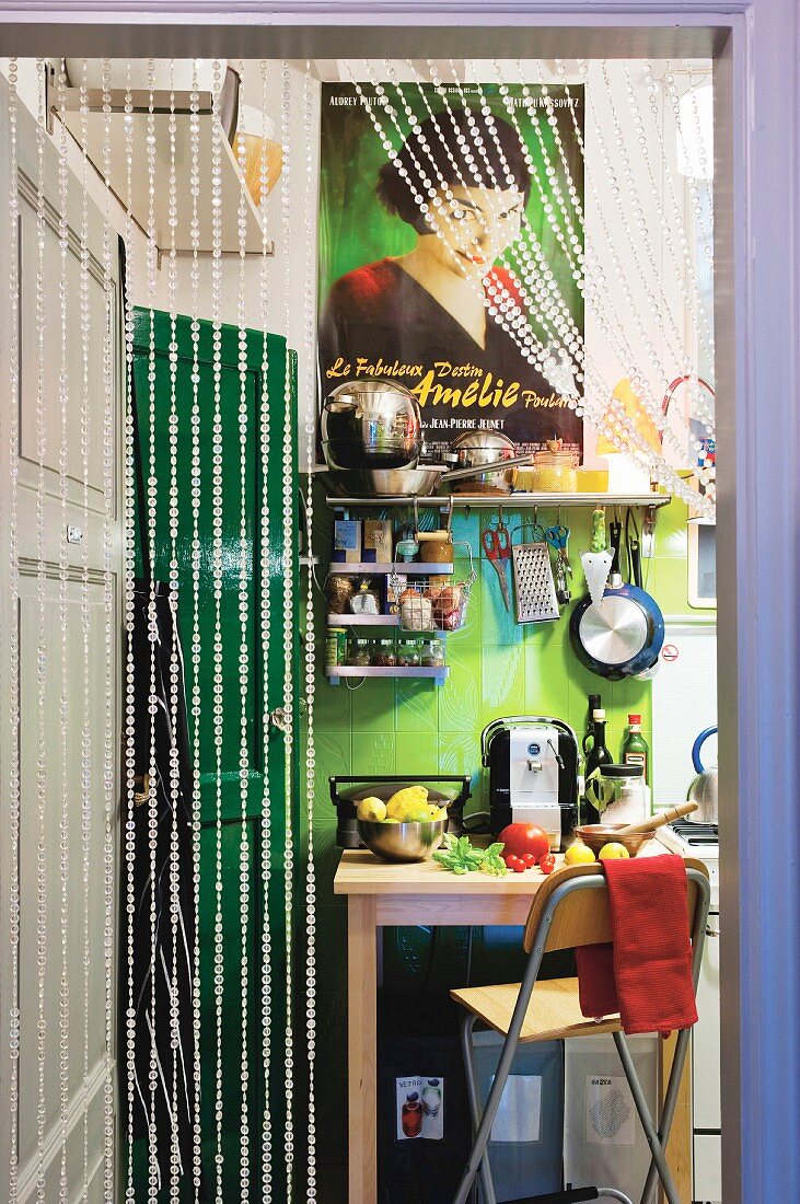 Blick durch Perlenvorhang in bunte Küche mit Filmplakat