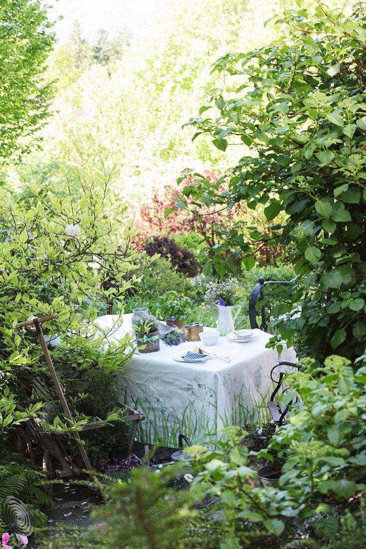 Gartenplätzchen mit bemalter Tischdecke und Krugvase