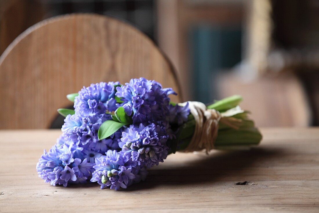 Bouquet of hyacinths tied with raffia on wooden table