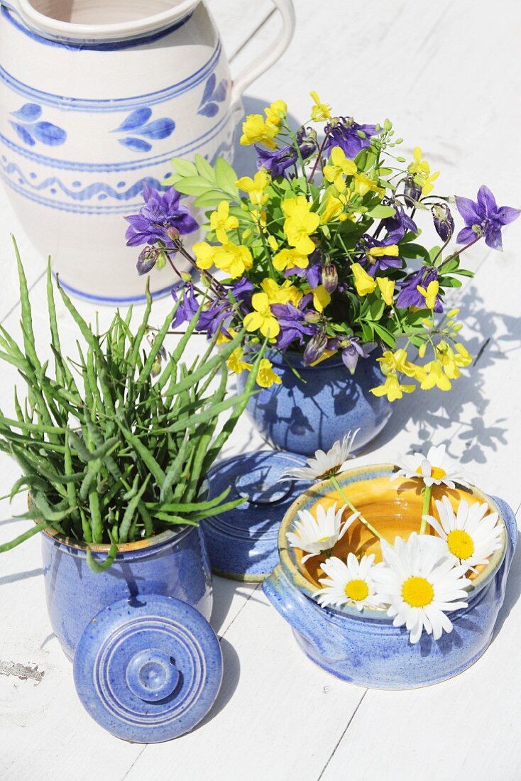 Rustic arrangement of stoneware pots and flowers on table