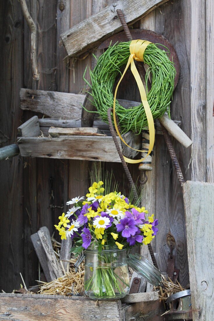 Flowers in preserving jar and wreath of rapeseed pods