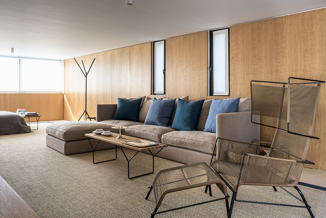 Designersessel und Sofa im Wohnzimmer mit Holzverkleidung