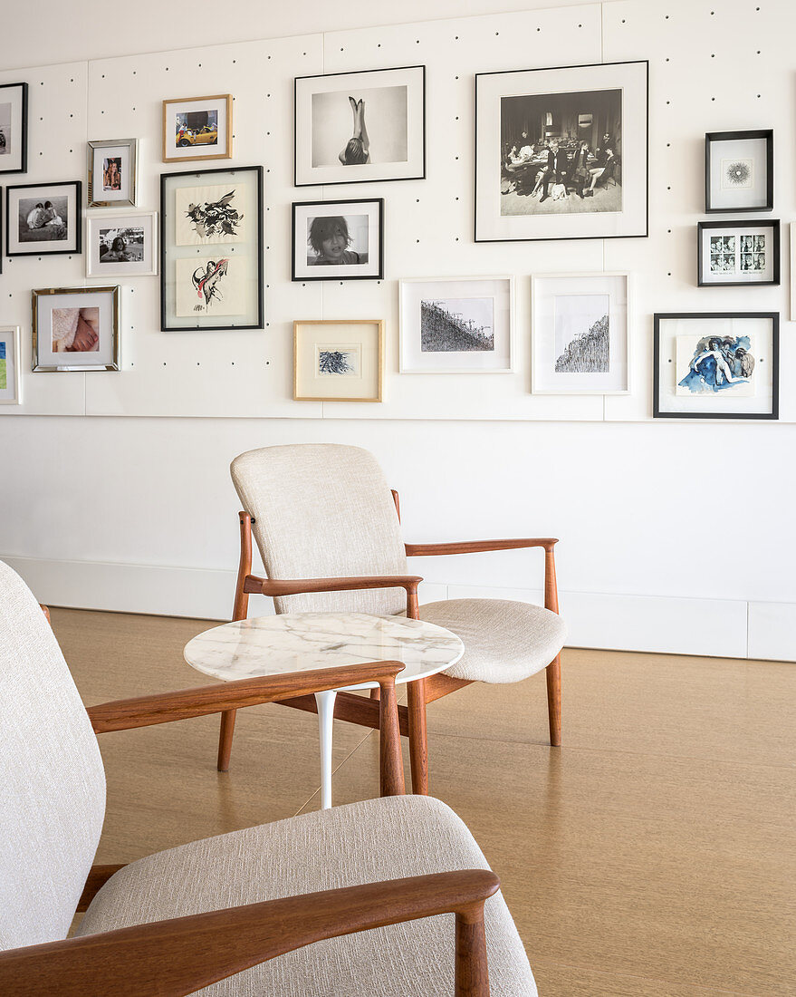 Zwei Sessel vor einer Wand mit Lochbrettern und Bildergalerie