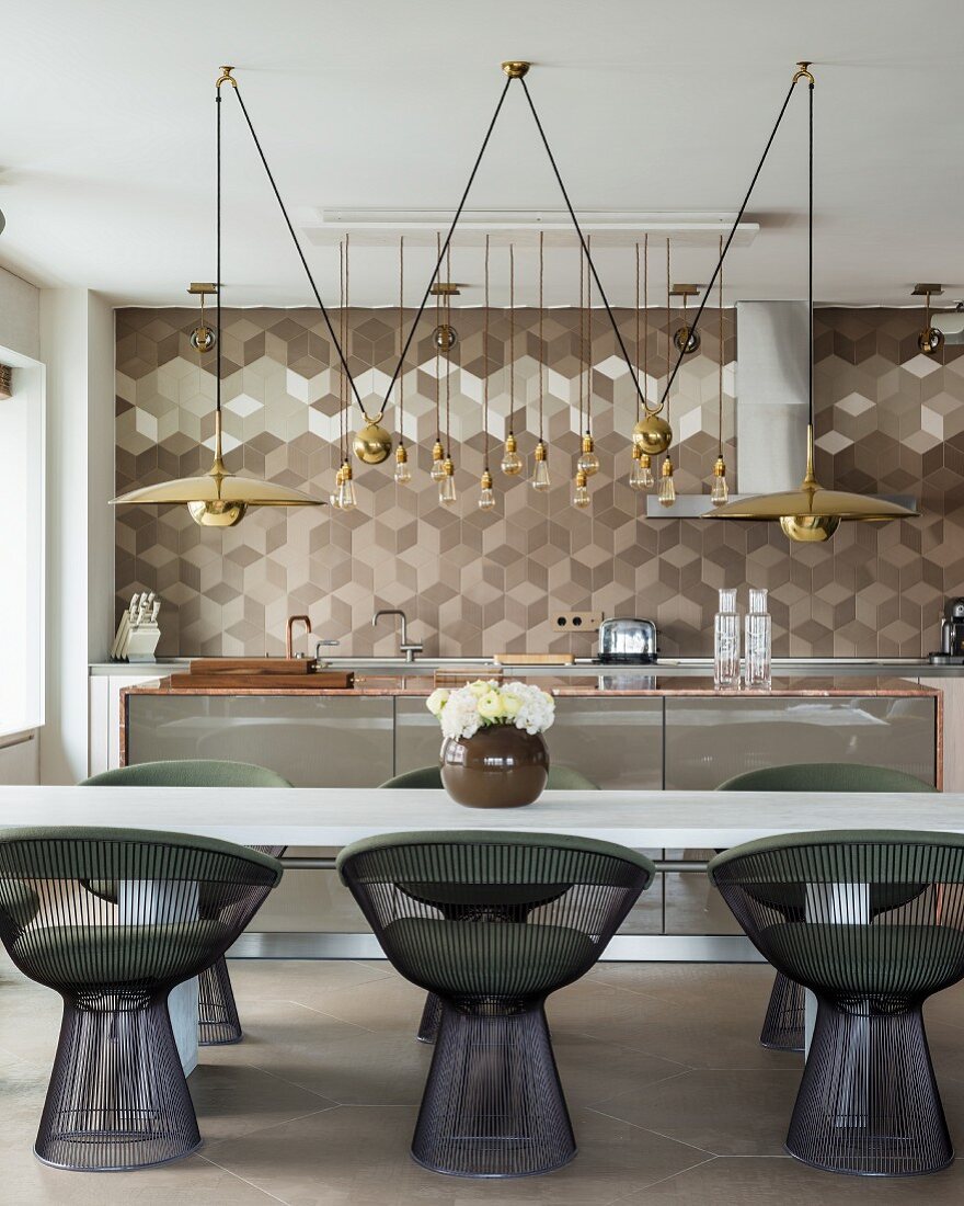 Retro Metallstühle mit Polsterauflagen an weißem Tisch vor edler Küche mit geometrischem Wandfliesenmuster