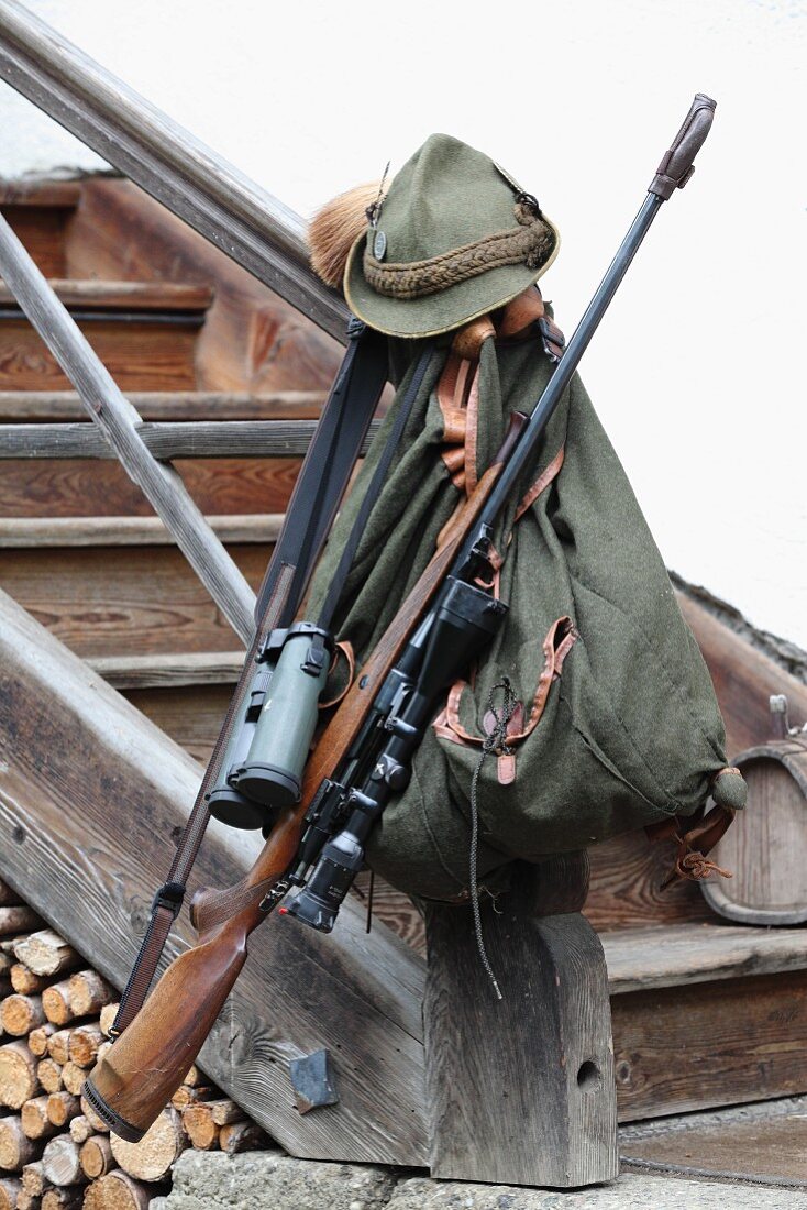 Backpack and hunting equipment on newel post of wooden staircase outside house