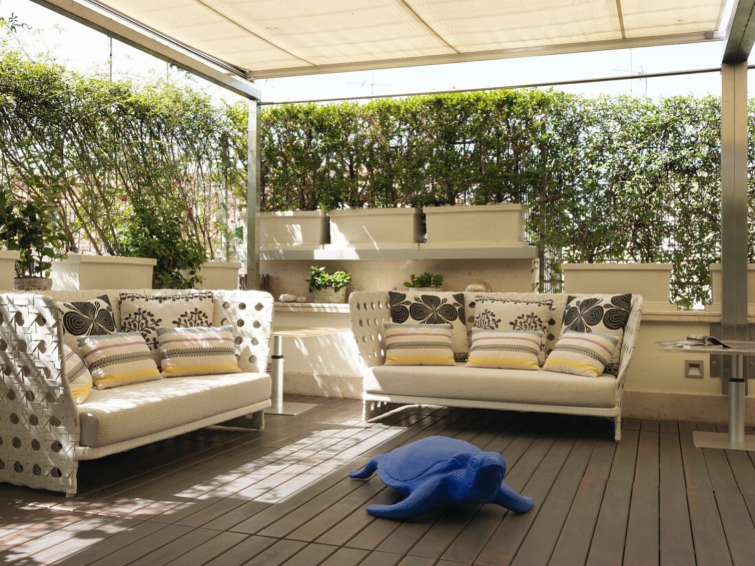Geschützte Terrasse mit blauer Kunst-Schildkröte vor Outdoor-Sofas mit Kissen
