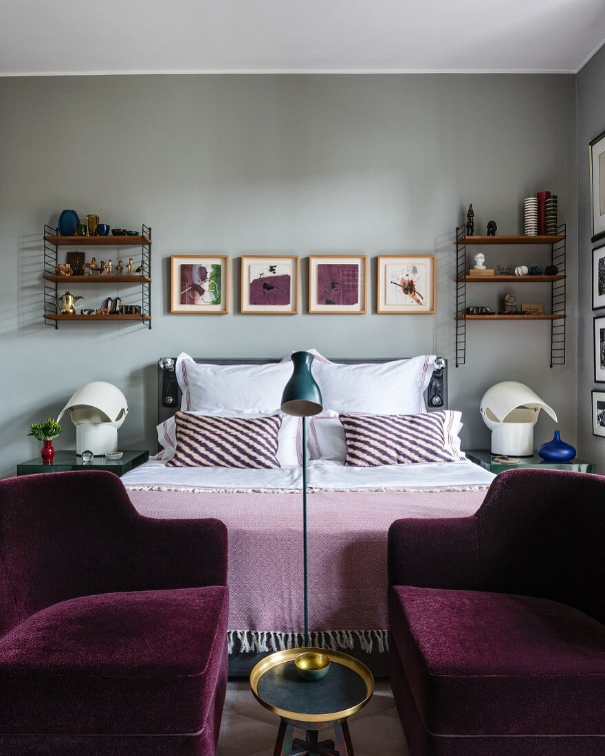 Two purple velvet armchairs at foot of bed with symmetrical accessories