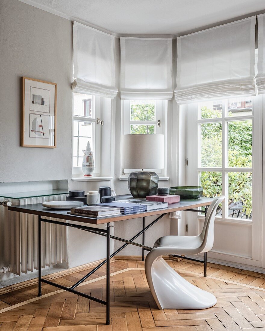 Designer furniture in workspace in window bay with herringbone parquet floor