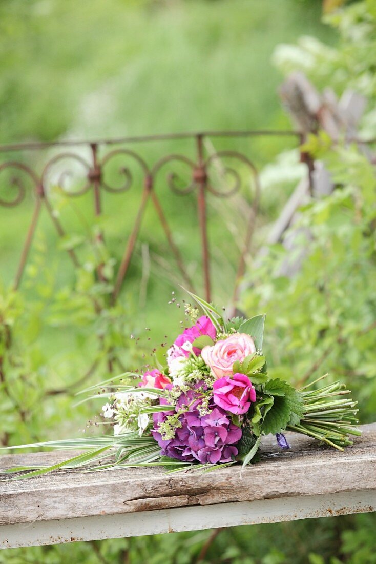 Üppiger Sommerstrauß mit pinken Blumen auf einem Holzbrett