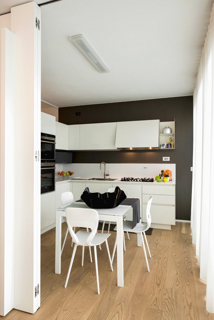 Blick in Küche in Schwarz-Weiß mit Esstisch und Holzboden