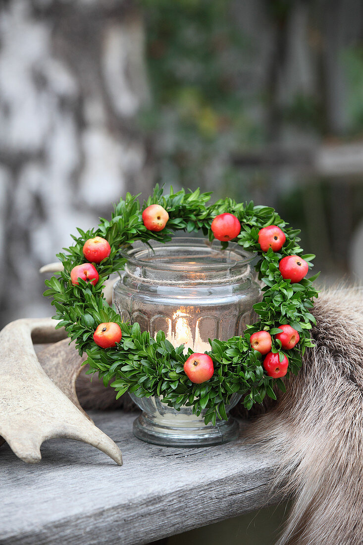 Small wreath of box and red crab apples around candle lantern