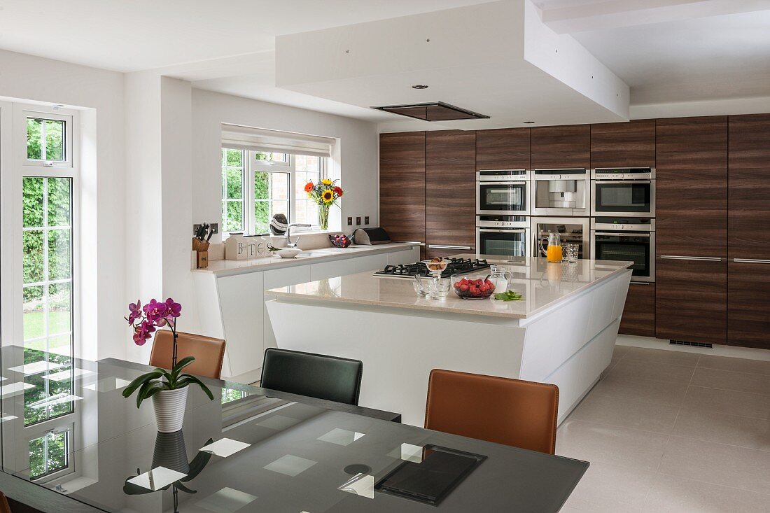 Island counter and dark wooden cupboards in modern kitchen-dining room