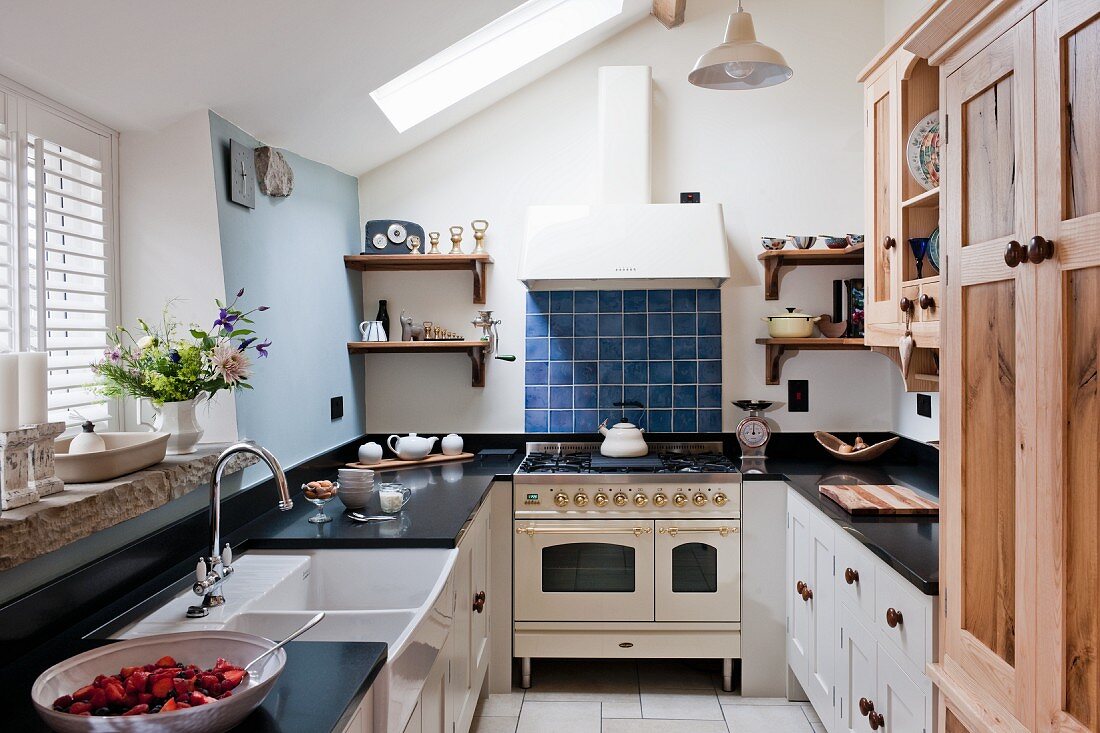 Landhausküche mit schwarzer Küchenarbeitsplatte und nostalgischem Gasherd