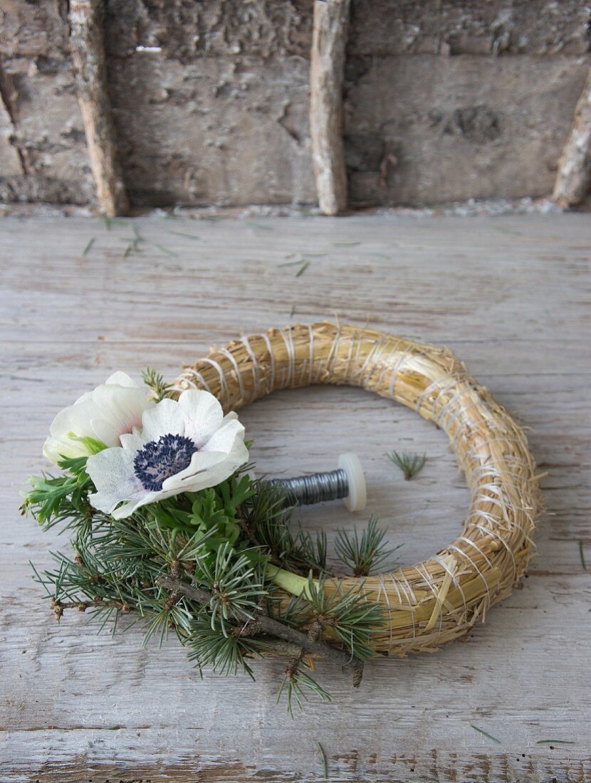 Straw wreath being decorated with anemones and larch twigs