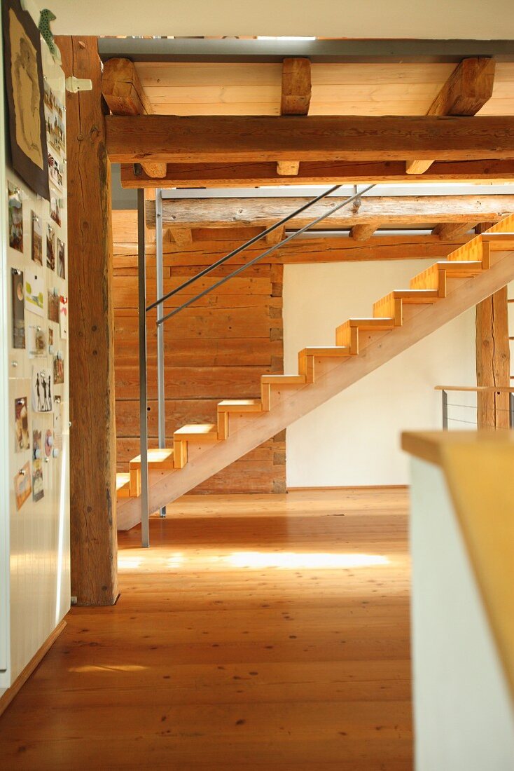 Modern wooden staircase in renovated period building with wood-beamed ceiling