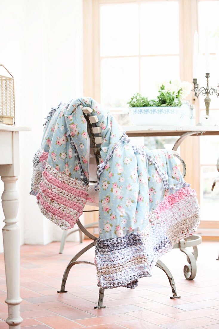 Floral blanket with crocheted edge draped over chair