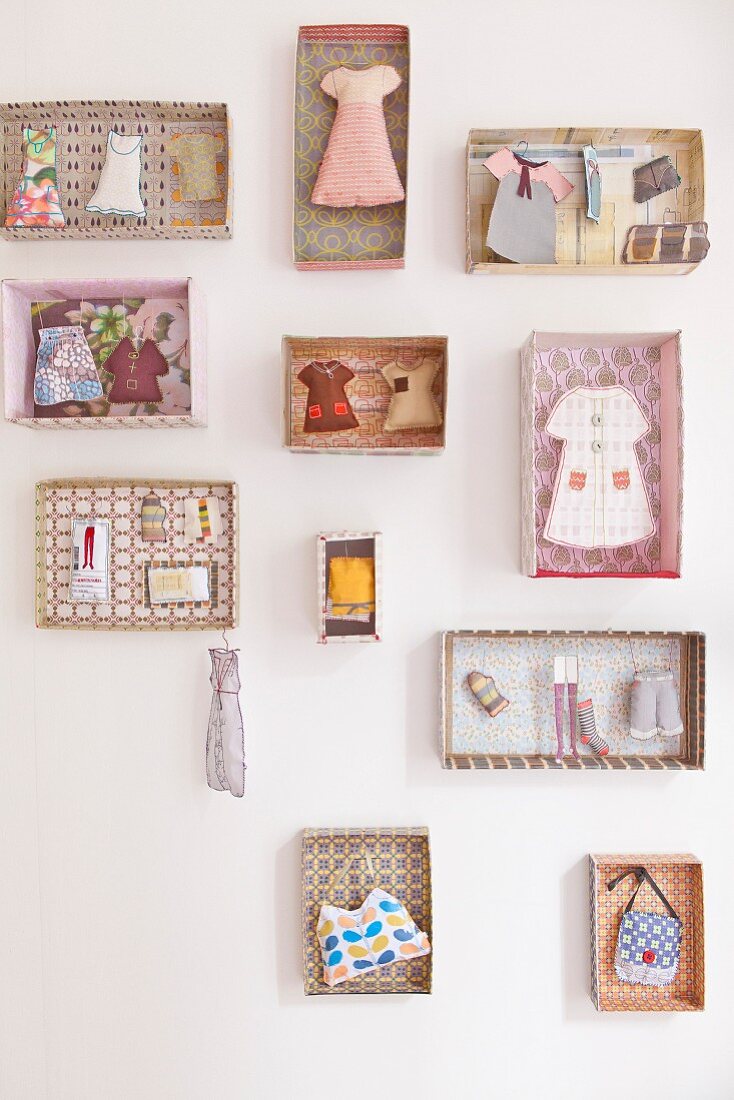 Miniatur-Kleidungsstücke und feminine Accessoires in einzelnen, gemusterten Pappschachteln