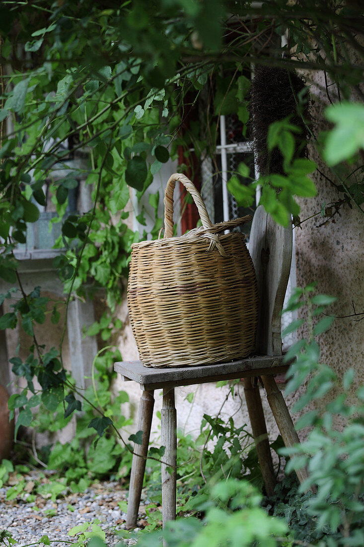 Basket on wooden stool against wall of house