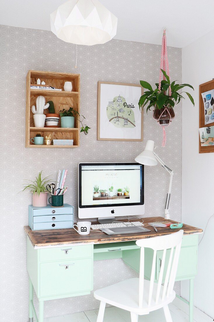 Mintfarbener Retro Schreibtisch mit Computerbildschirm und weisser Holzstuhl in Zimmerecke