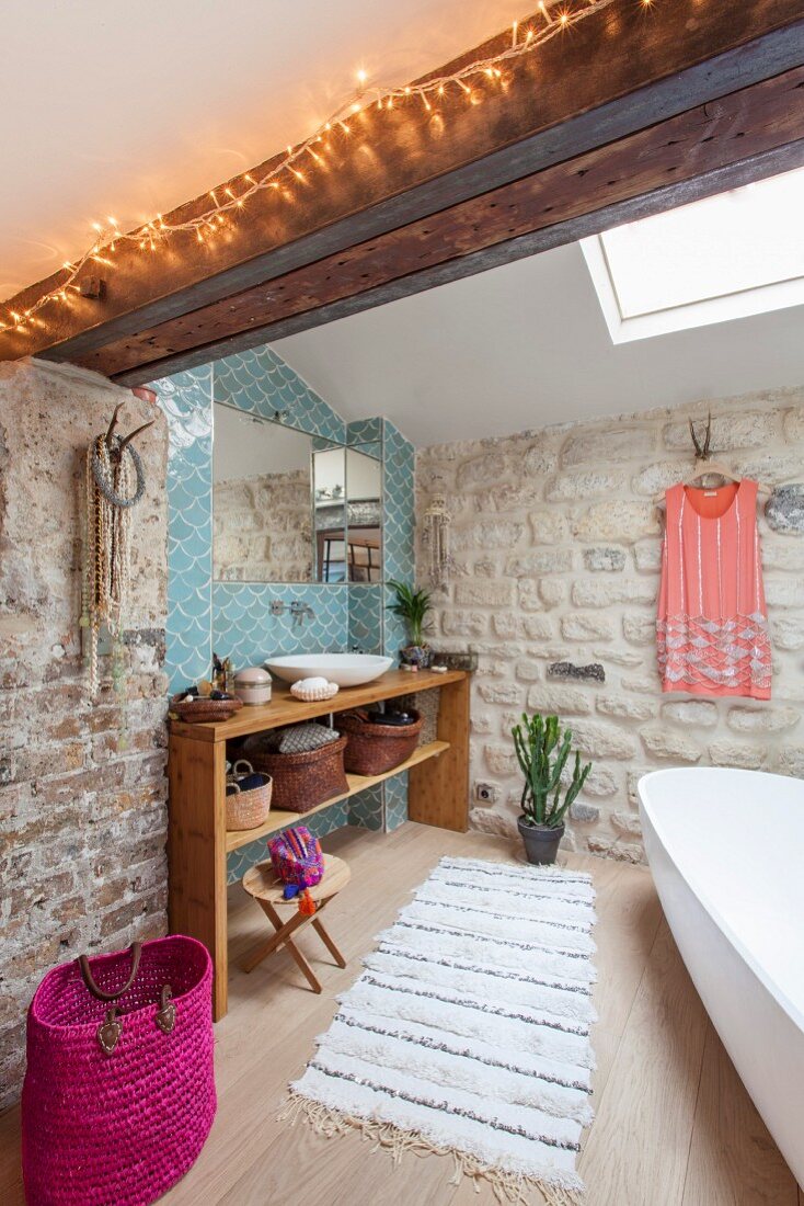 Exposed masonry and wooden washstand against blue tiles in bathroom