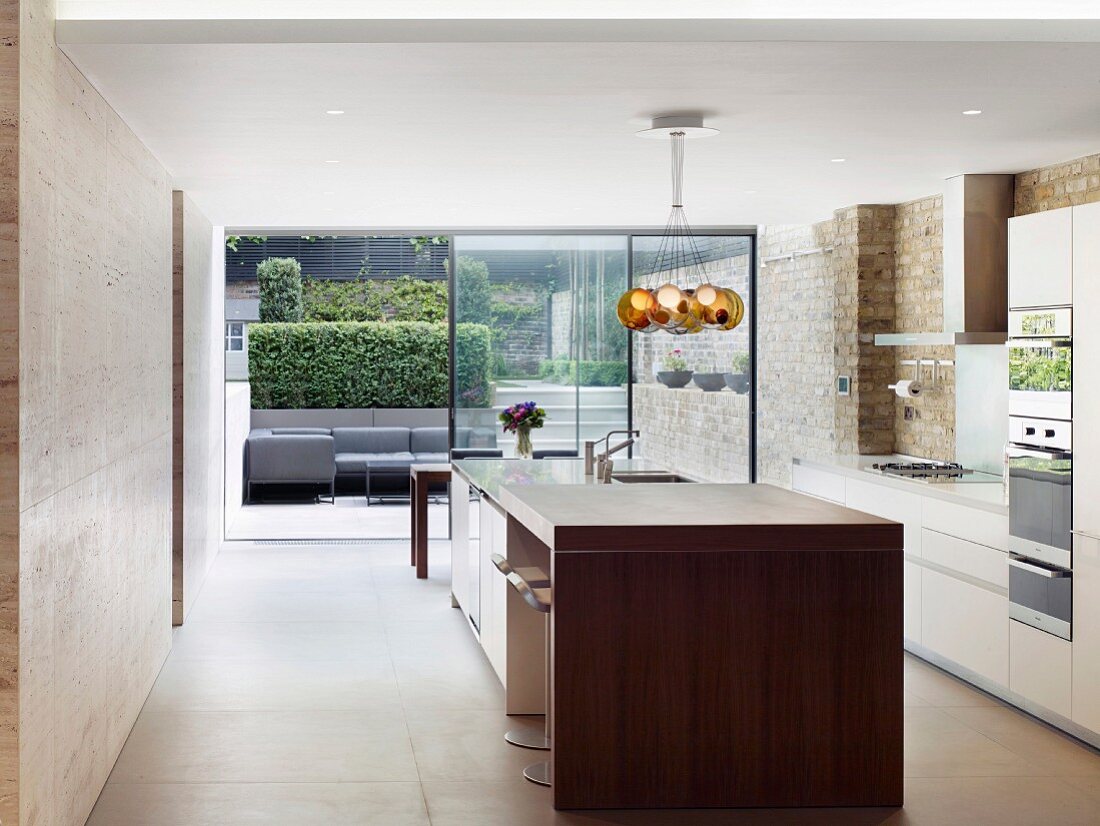 Moderne Designerküche mit Glasfront und Blick auf Terrasse in modernisiertem Altbau