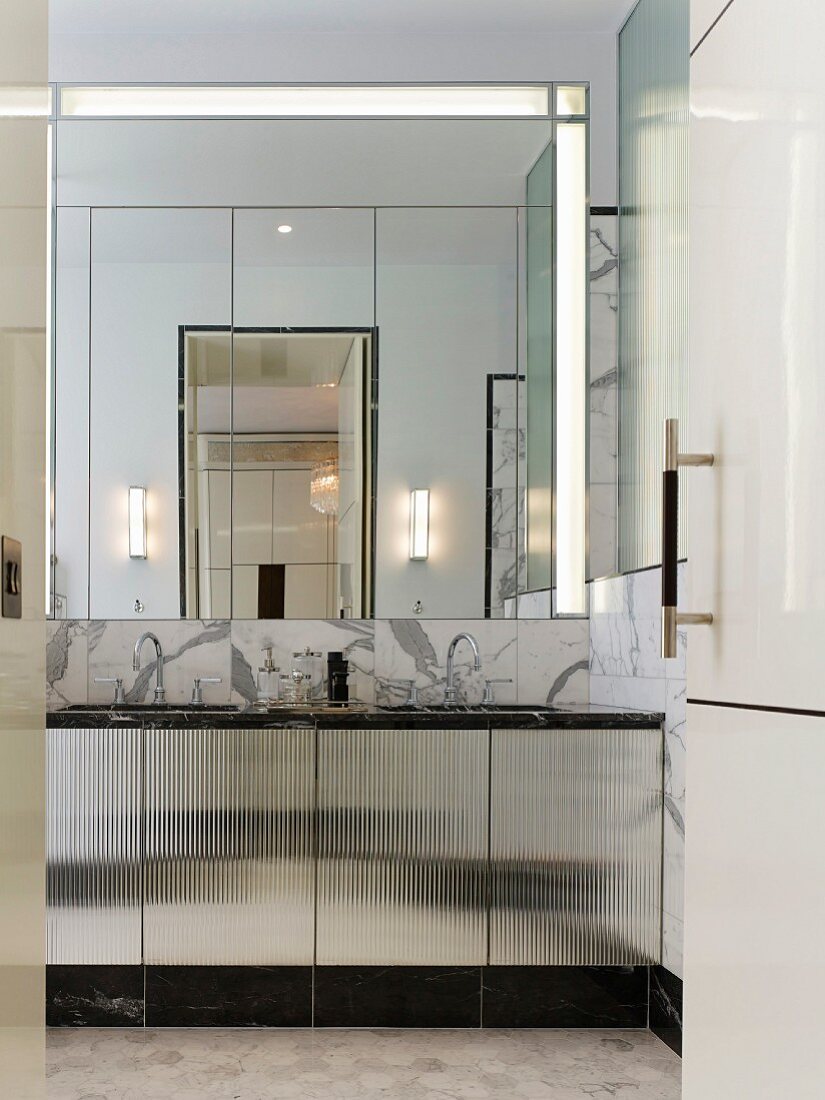 Blick in elegantes Bad mit Doppelwaschbecken, Marmorverkleidung und großem Wandspiegel