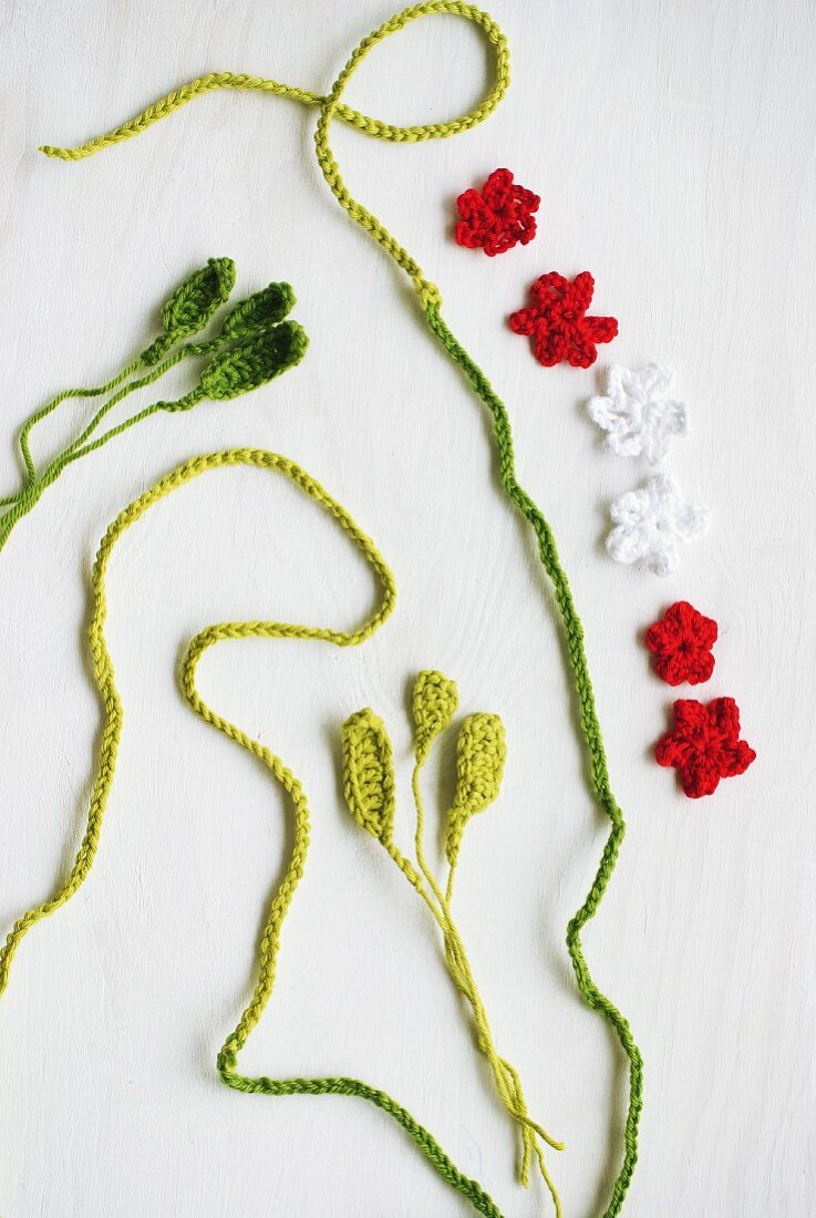 Red and white crocheted flowers and green crocheted cord