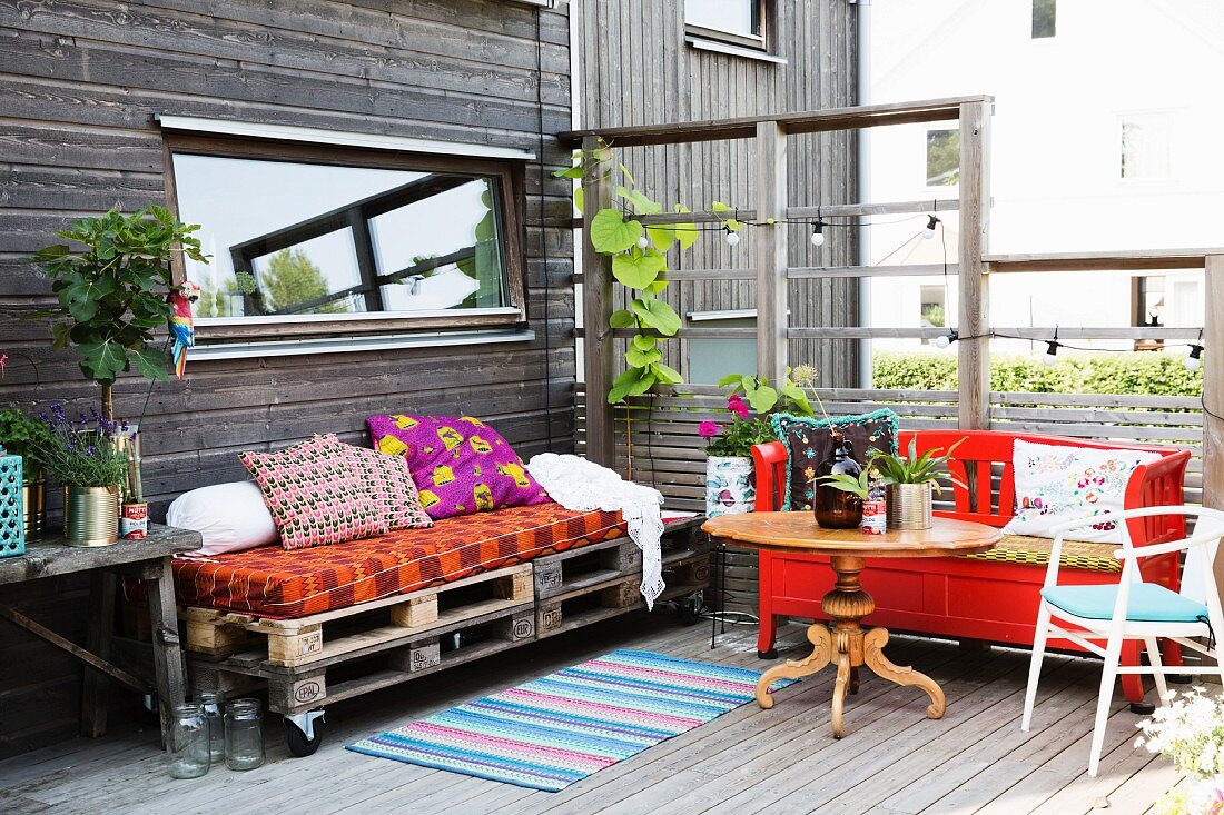 DIY-Palettenmöbel und rot lackierte Sitzbank auf Holzterrasse