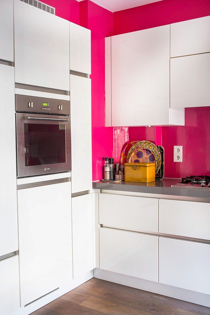 Moderne weiße Küche mit pinker Wand