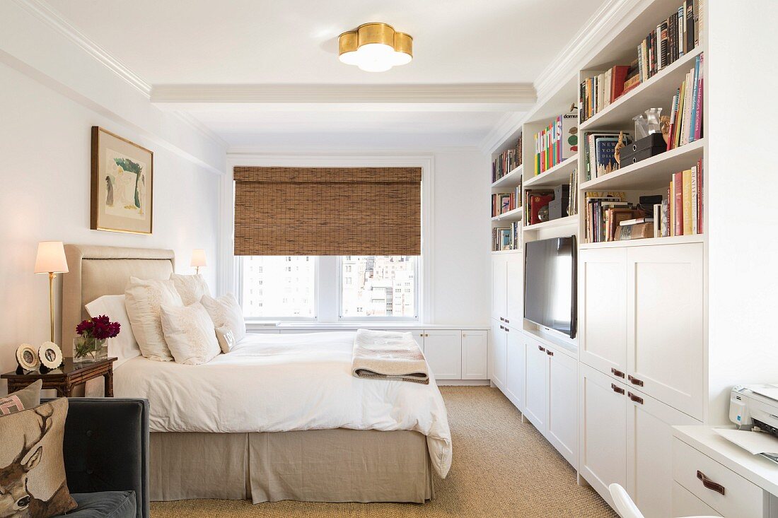 Schlafzimmer mit weißer Schrankwand und Doppelbett mit gepolstertem Kopfteil