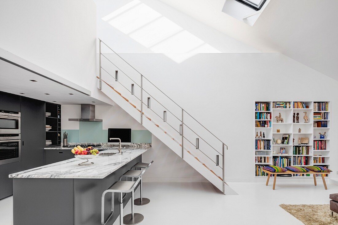 Stahltreppenlauf zur Galerieebene über anthrazitfarbener Designerküche in offenem Wohnbereich