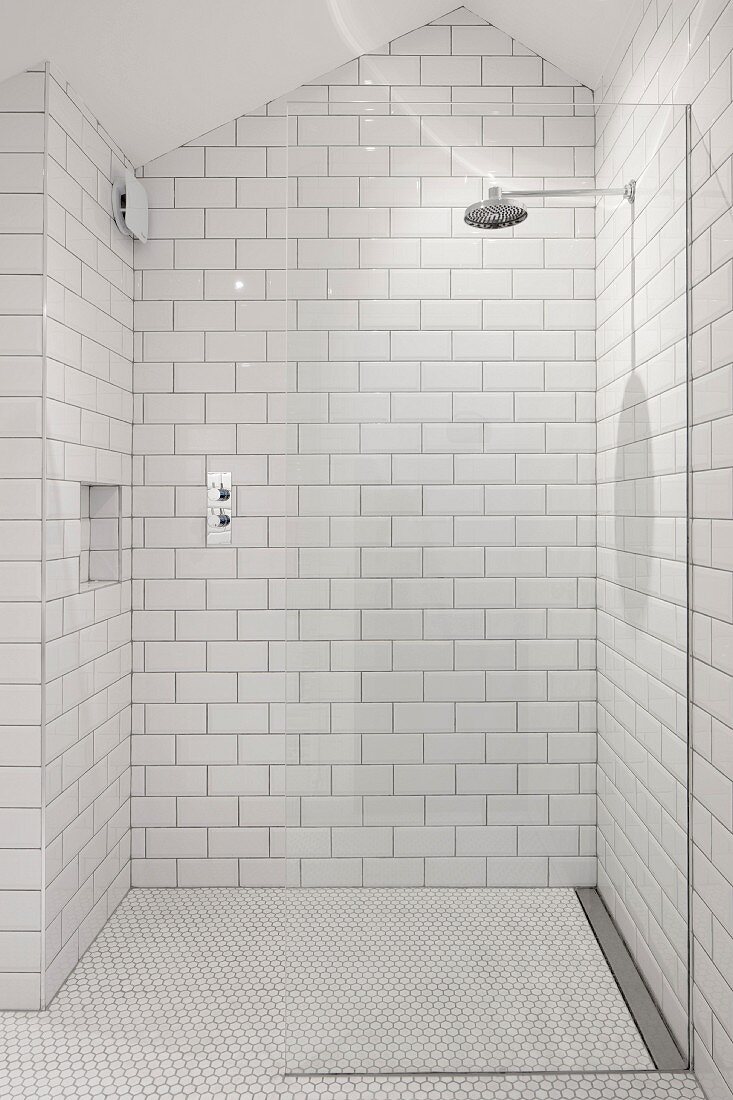 Weiß gefliester Duschbereich mit Regendusche im Dachgeschoss