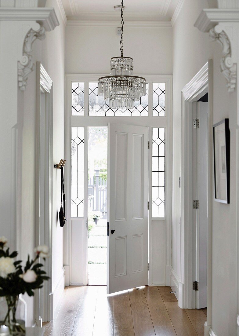 Elegant, traditional house entrance with half-open front door and leaded glass window elements