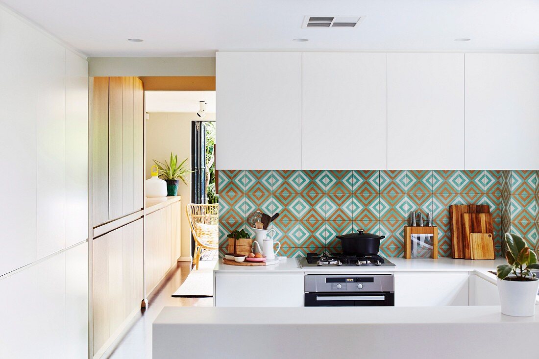 Splash guard with patterned wall tiles in a white, open kitchen