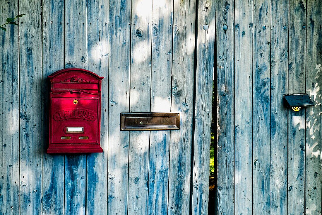 Briefkästen an einer verwitterten blauen Bretterwand