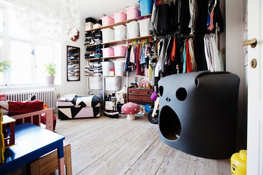 Black foam play den in front of open-fronted shelving system in child's bedroom