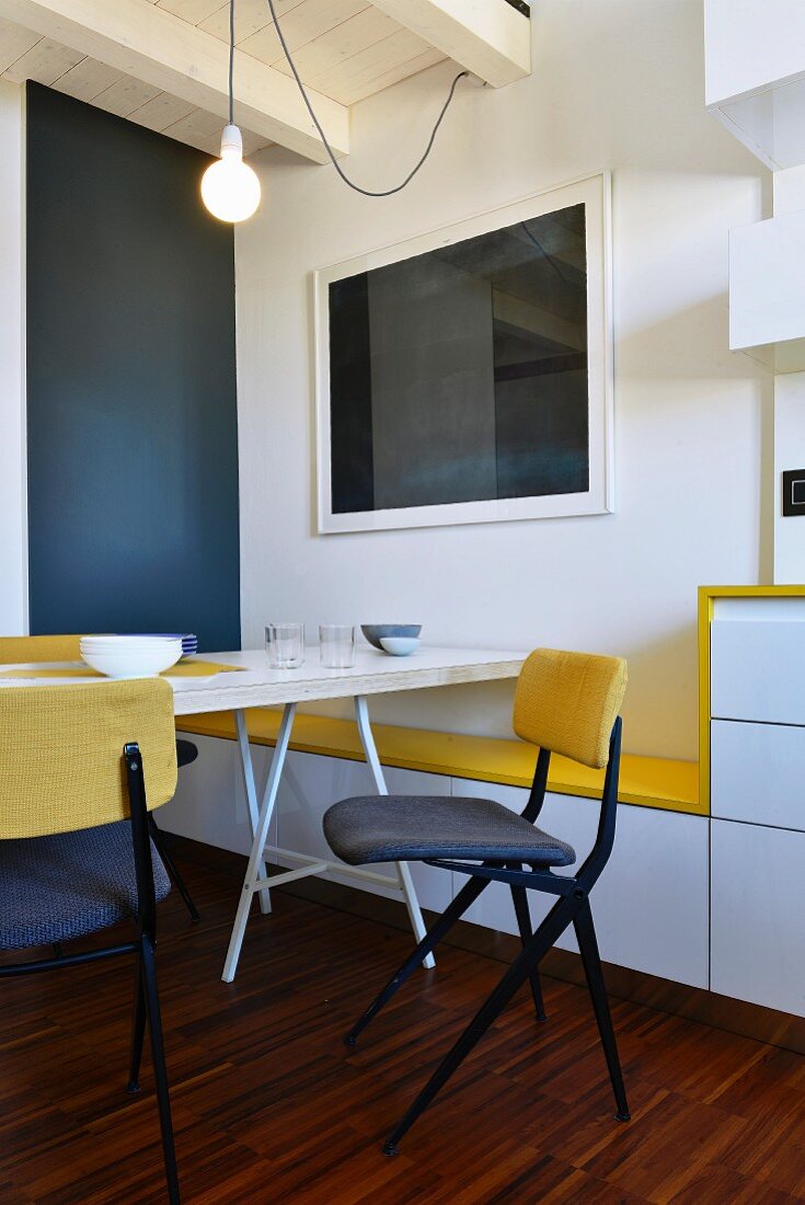 Minimalist dining chair and table next to wall with yellow seat on custom bench