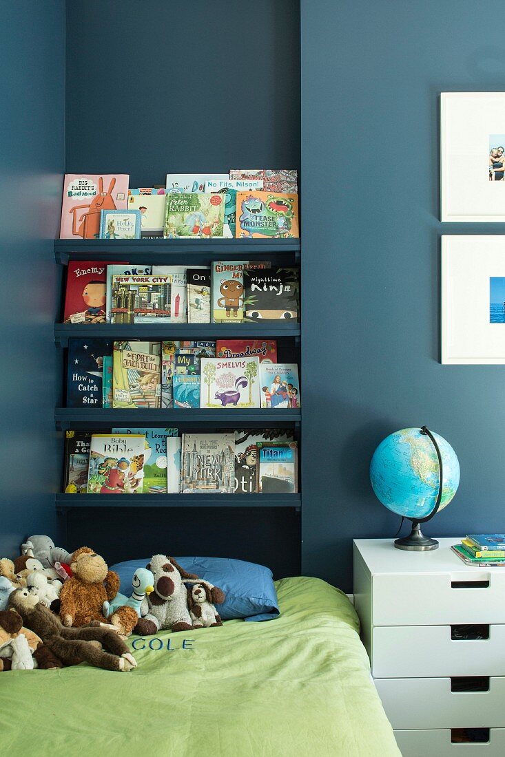 Bookcase above bed in child's bedroom with blue wall