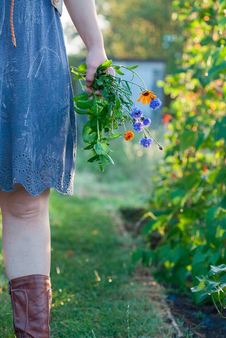 Woman standing in garden holding flowers