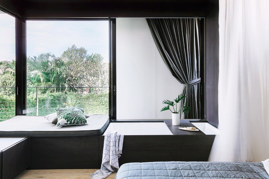Elegante Schlafzimmerecke mit eingebauter Badewanne vor Fenster