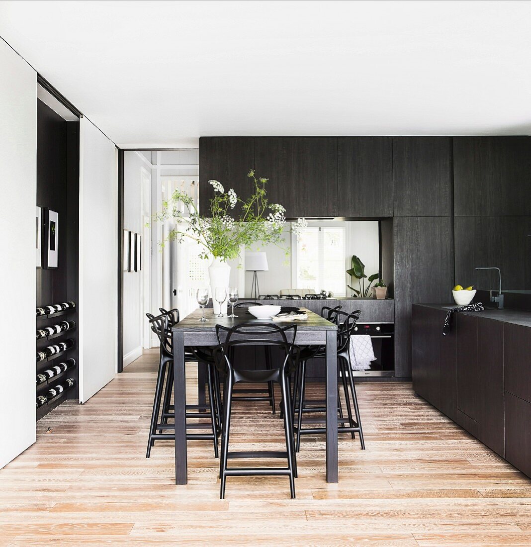 Thekentisch mit schwarzen Barhockern in eleganter, massgefertigter Küche mit schwarzen Holzfronten